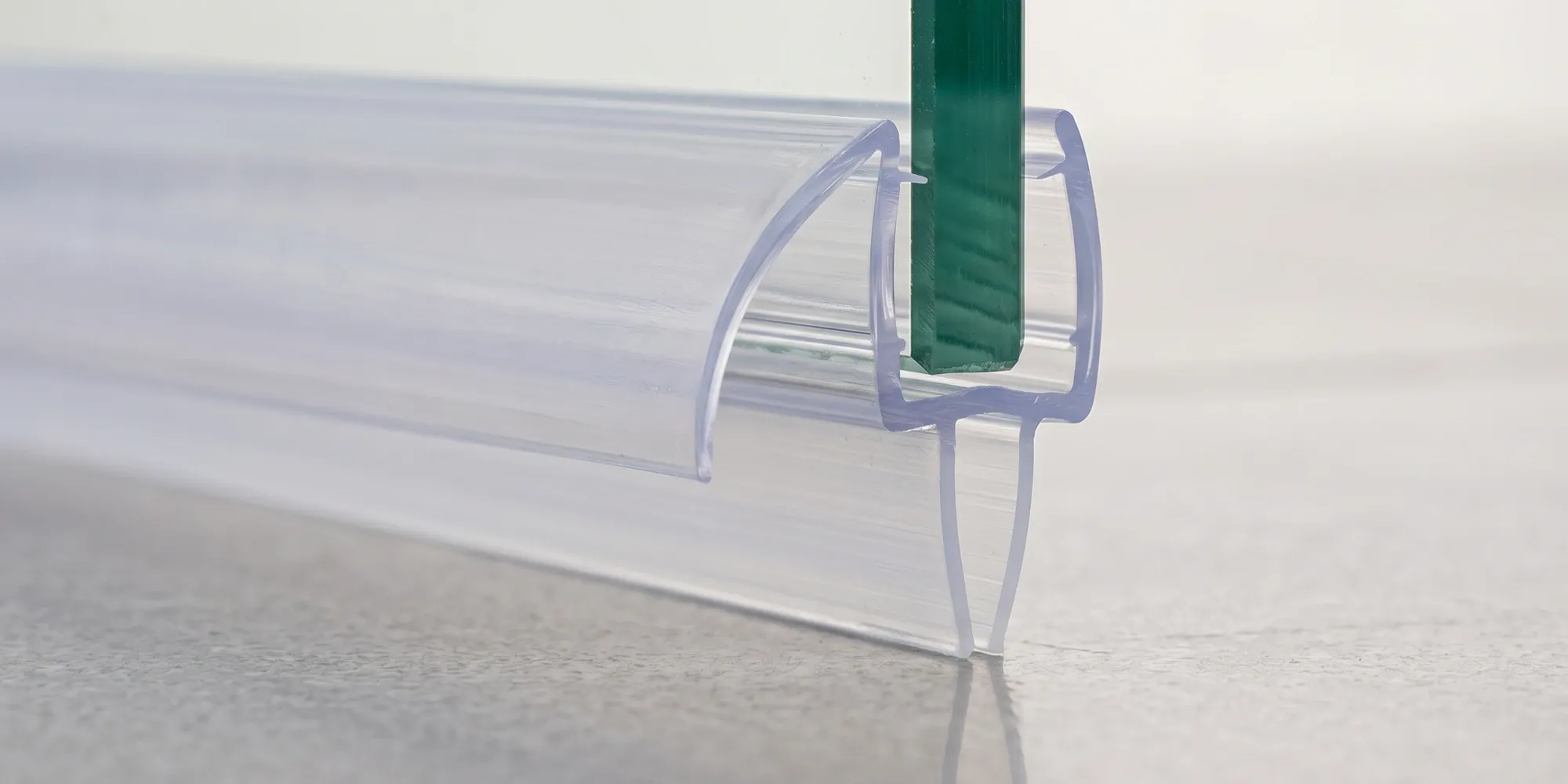 Vinyl bottom sweep gripping the lower edge of a frameless shower door glass panel