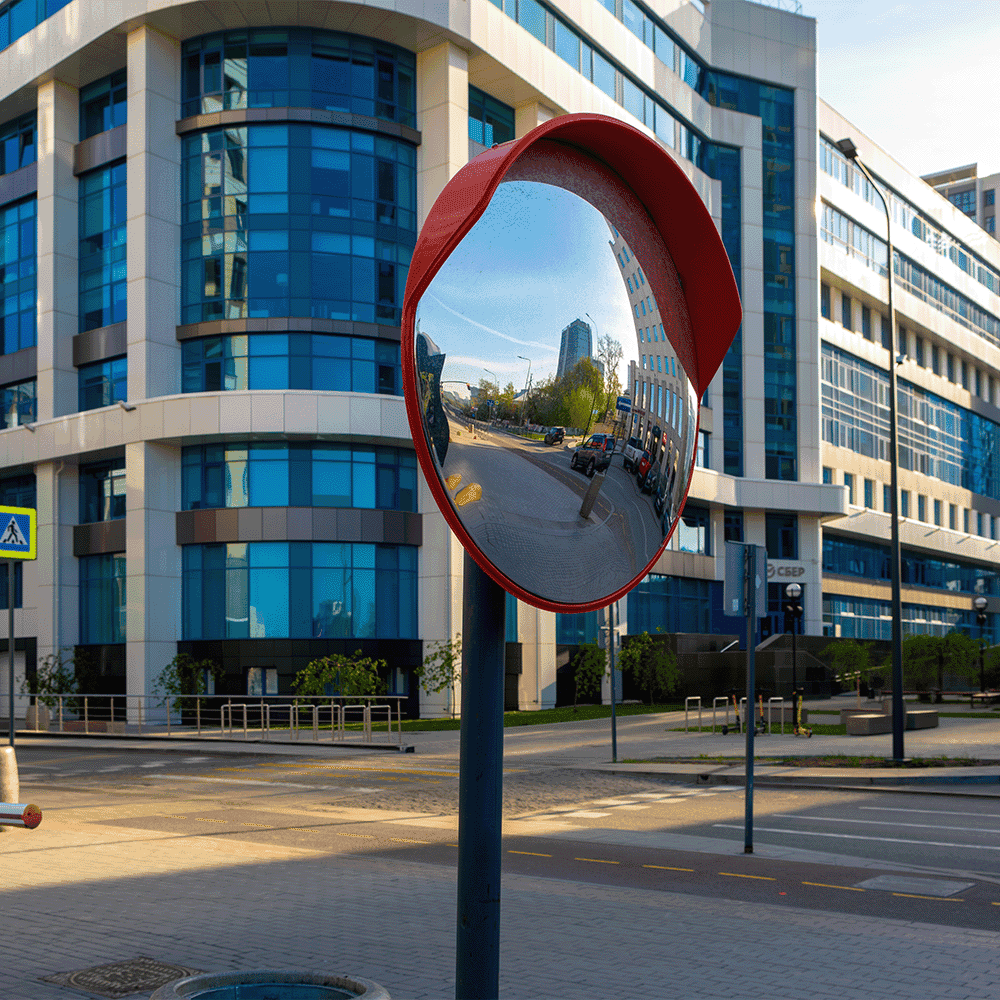 Reflective street mirror with surrounding modern glass buildings, illustrating the impact of custom glass solutions, suitable for shower doors, table tops, and mirrors.