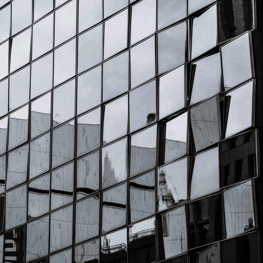 Reflective glass facade showcasing custom glass design, ideal for applications like shower doors, table tops, and mirrors with tempered and beveled glass edge options.