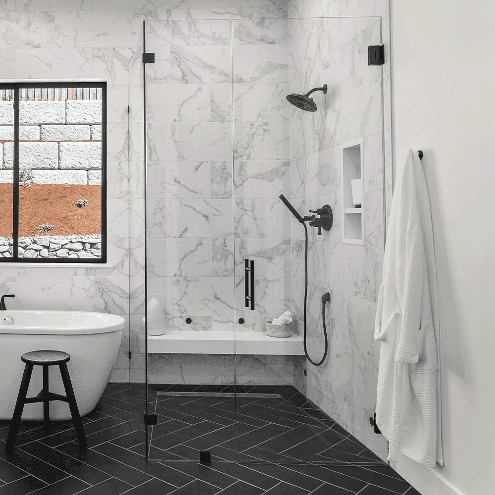 Custom glass shower doors in a modern bathroom with marble tiles