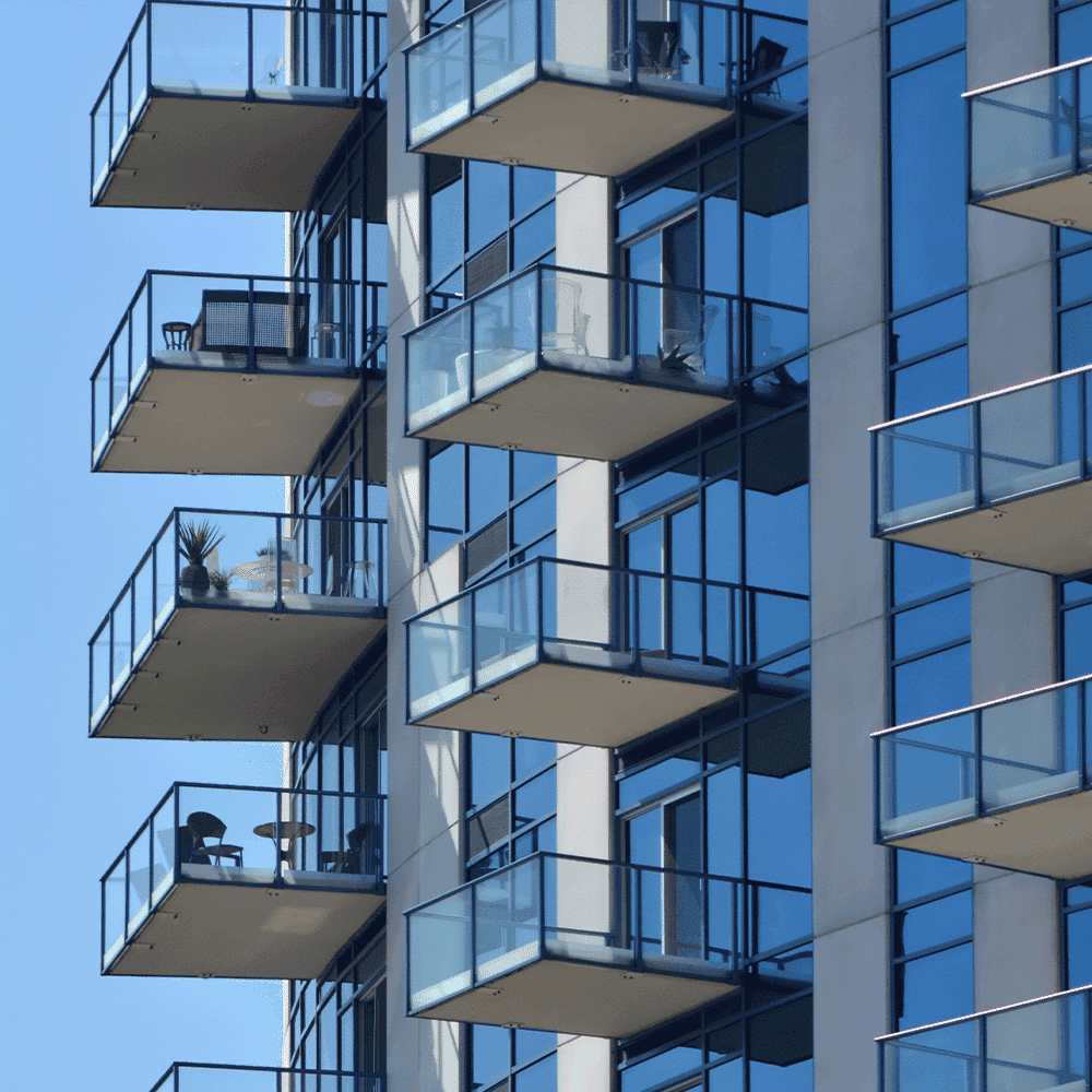 Balconies with glass railings on a modern building, showcasing custom glass designs and tempered glass features.
