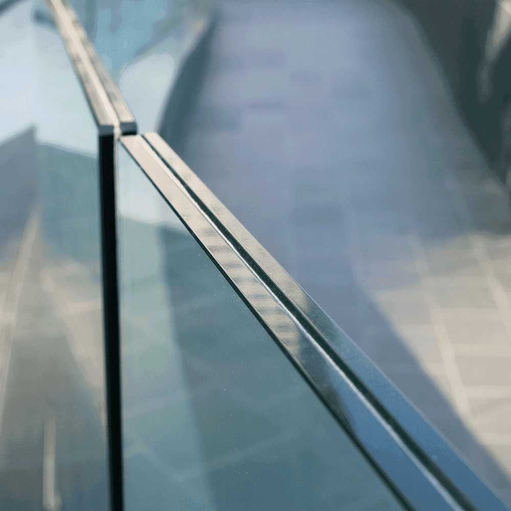 Close-up of a sleek custom glass balcony railing with a tempered glass edge, showcasing modern design and quality craftsmanship.