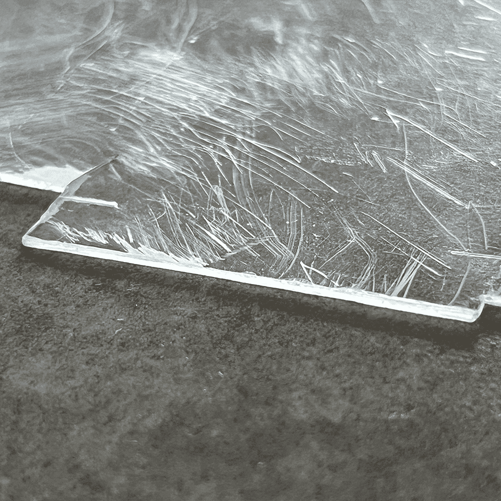 Close-up of scratched tempered glass sheet, ideal for custom glass applications like shower doors, table tops, and beveled edges.