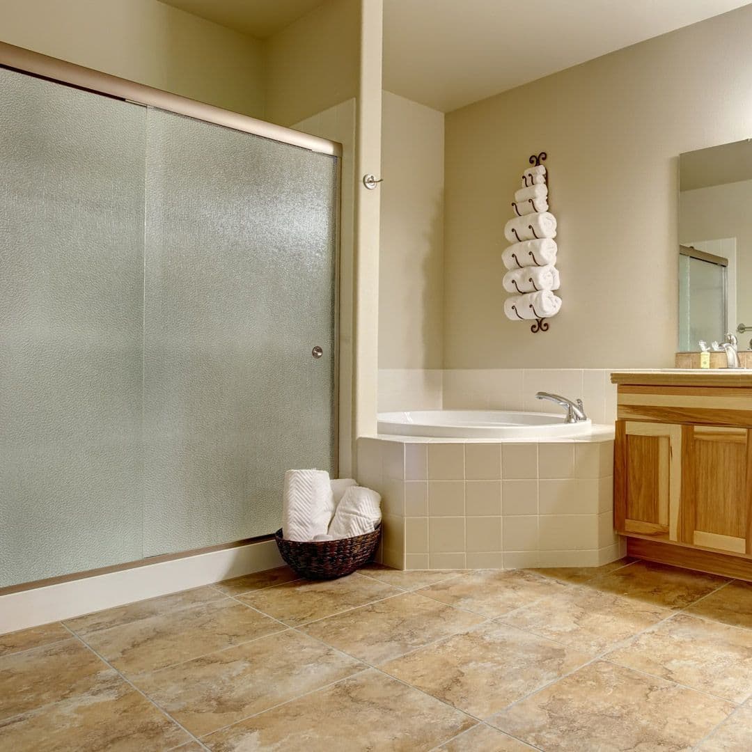 Modern bathroom featuring a clear tempered glass shower door, a spacious bathtub, and a large mirror, highlighting custom glass design elements.