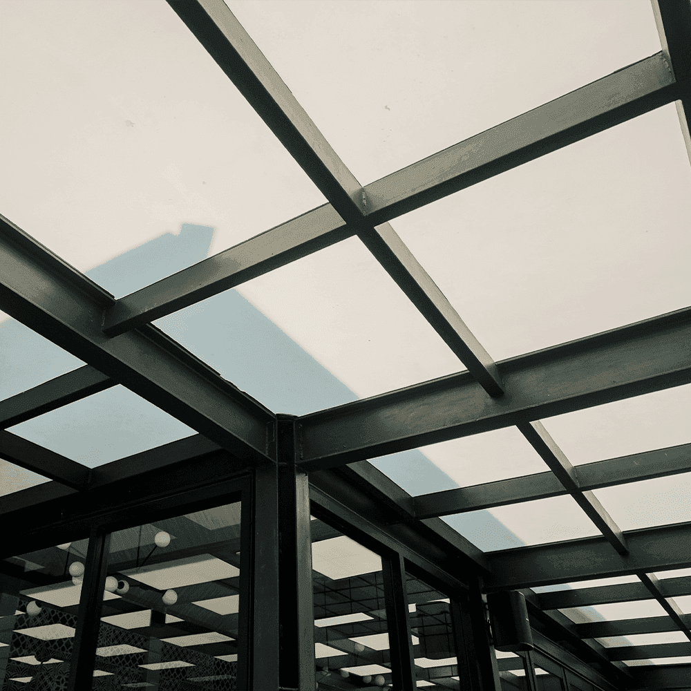 Interior view of a glass structure showcasing custom glass panels with a modern design, ideal for shower doors, table tops, and mirrors, featuring durable tempered glass and a sleek beveled glass edge.