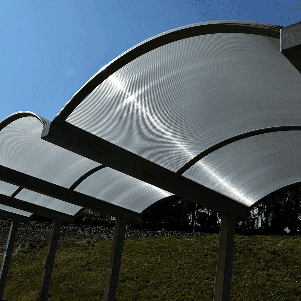Curved glass structure under a bright sky, showcasing custom glass solutions.