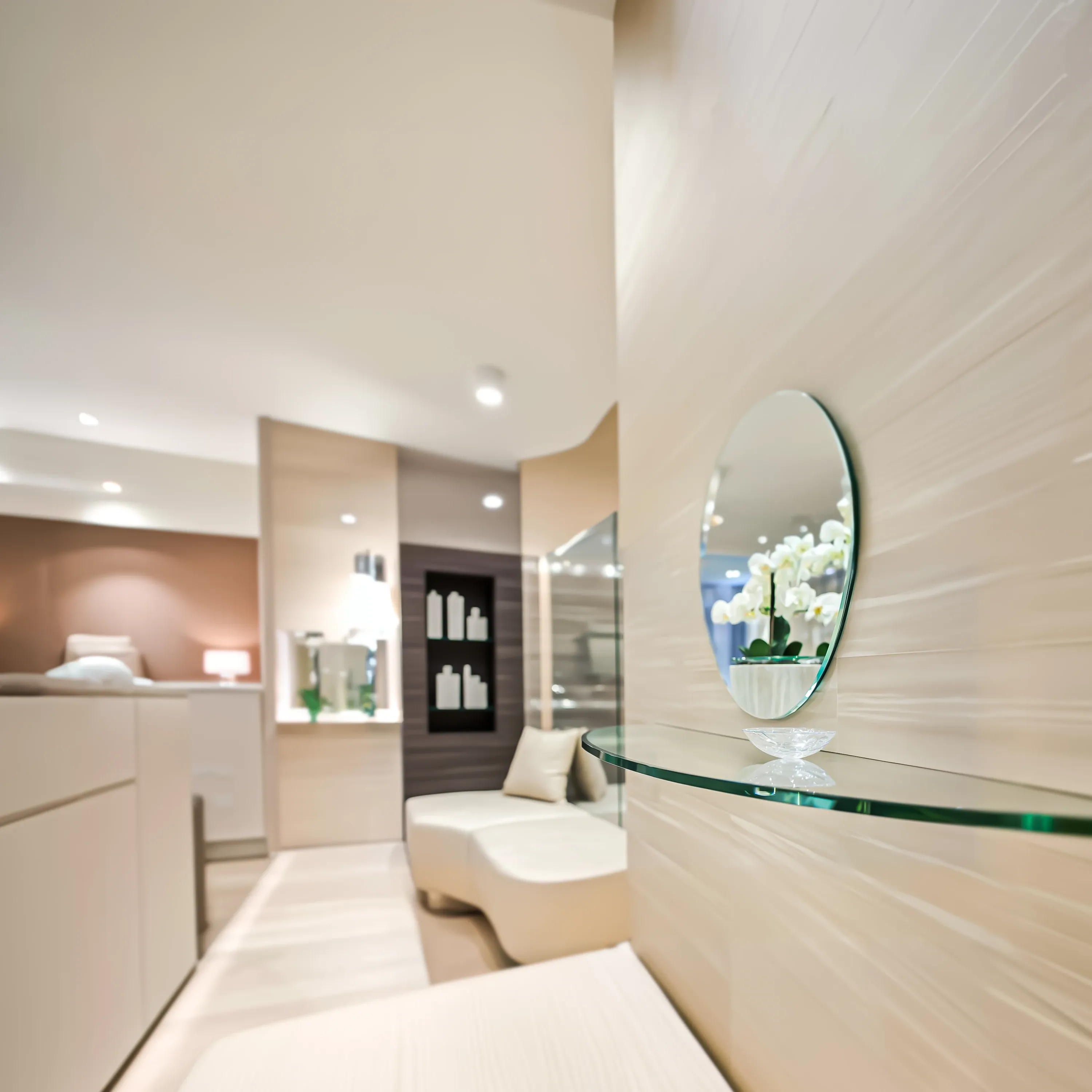 The serene and modern interior of a luxury spa, with a close-up on a floating glass shelf holding a small oval mirror.