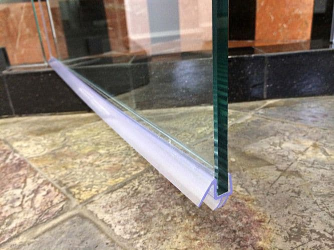 Close-up of a shower door featuring custom tempered glass with a clear bottom seal
