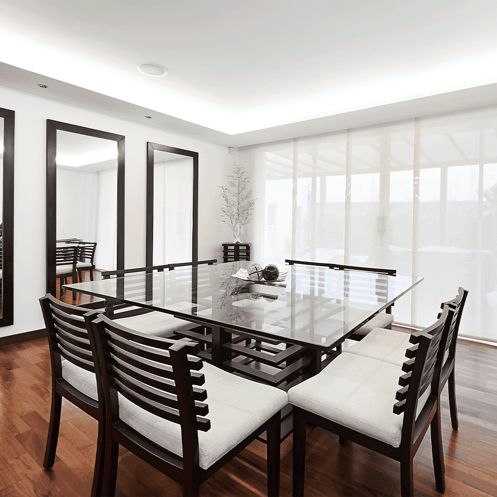 A modern dining room featuring a sleek glass table top