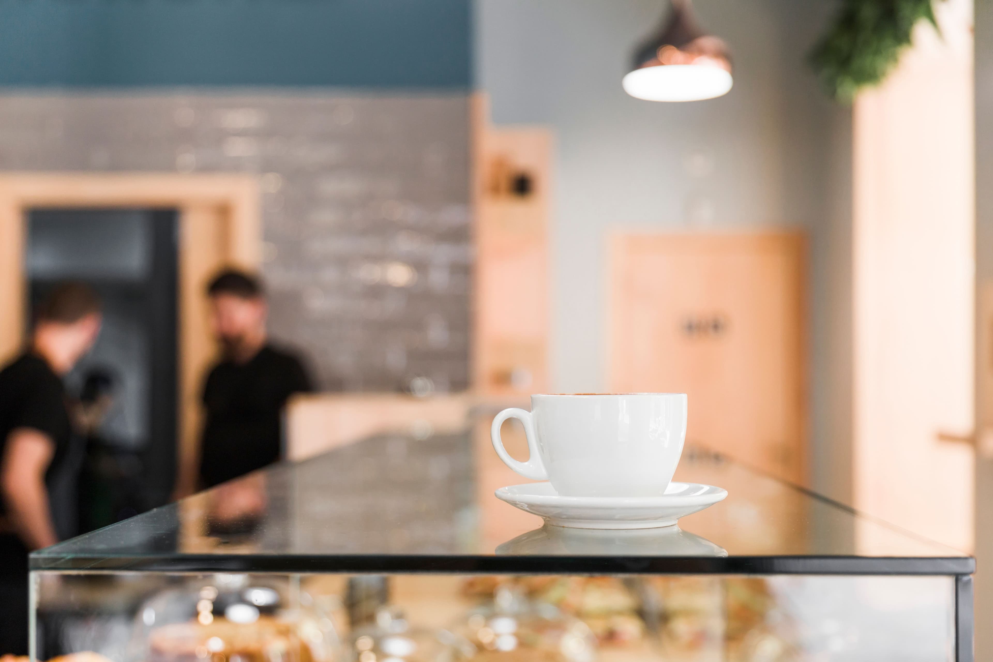 Custom glass table top featuring a white coffee cup, showcasing the clarity and elegance of tempered glass in a modern cafÚ setting.