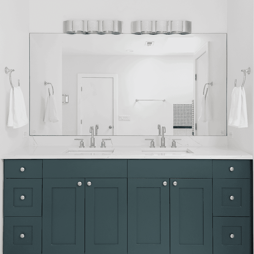 Bathroom featuring a sleek custom mirror above a dual sink vanity with a modern design, showcasing tempered glass fixtures and elegant cabinetry.