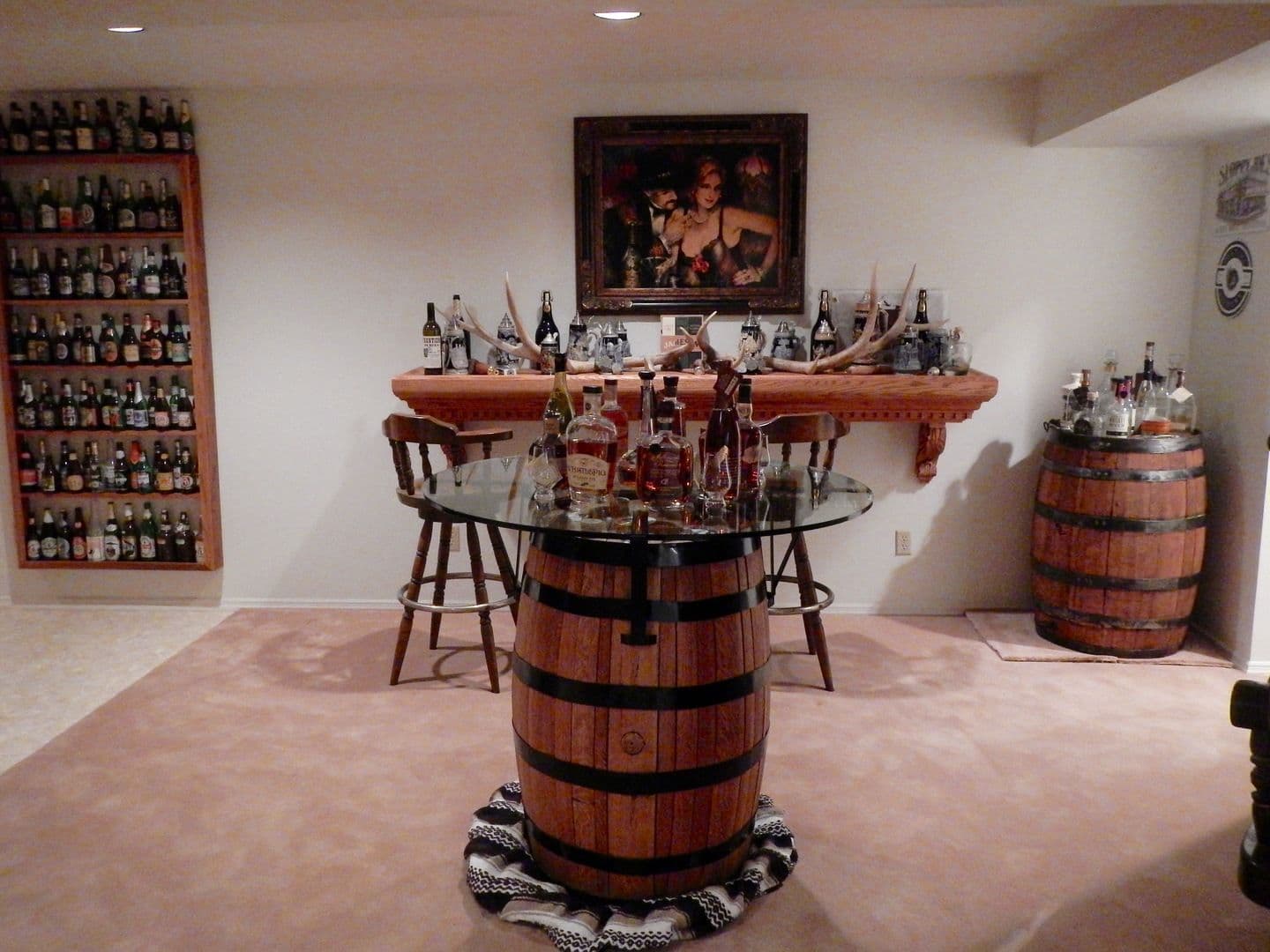 Rustic home bar with whiskey barrels, liquor bottles, and wall-mounted bottle display