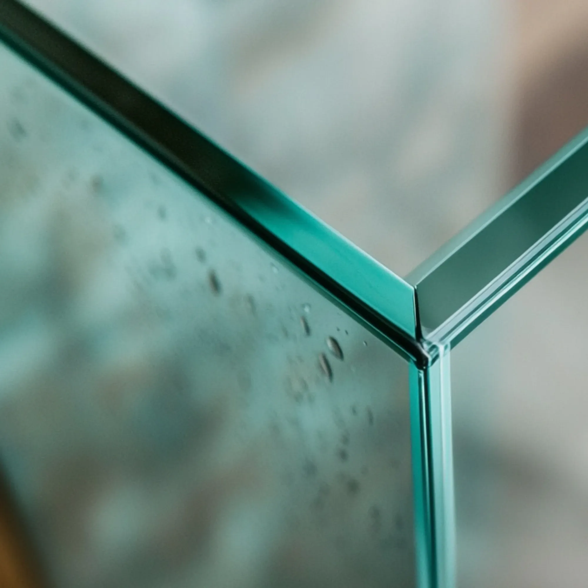 A close-up shot shows the corner of a glass tank, highlighting the beveled edges and polished seams that create a smooth, modern look.