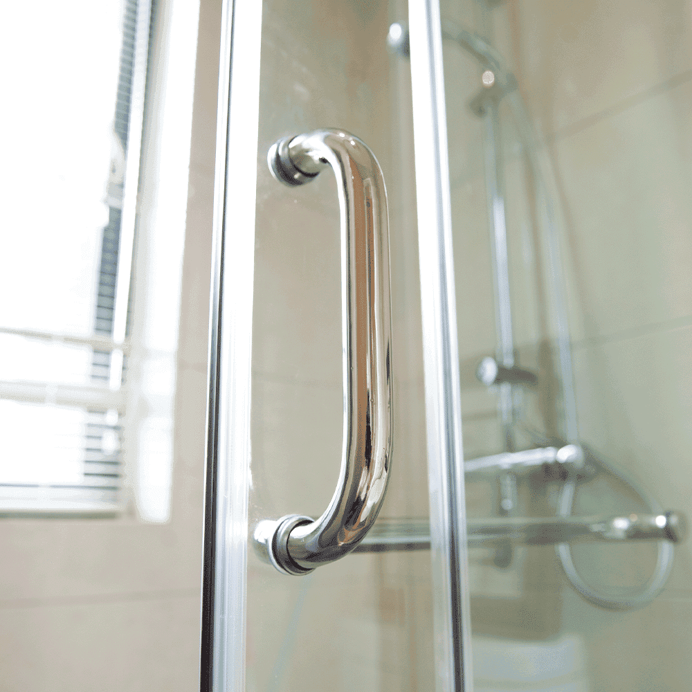 Close-up of a sleek chrome handle on a custom glass shower door, showcasing high-quality tempered glass and modern design elements.