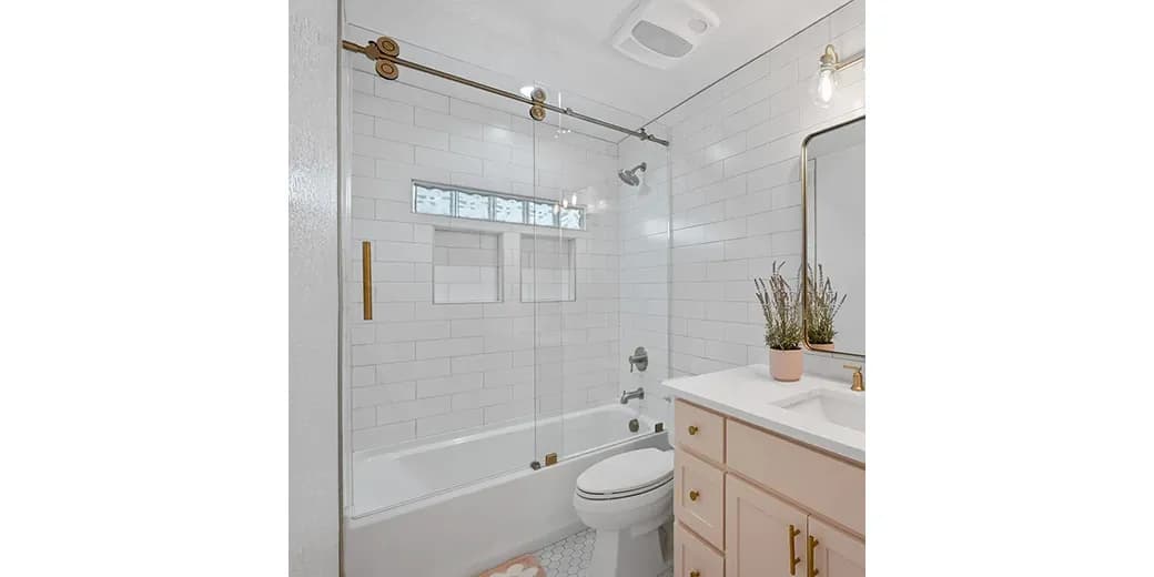 Stylish glass shower door with gold hardware, paired with a white subway tile backdrop, modern vanity, and hexagon tile flooring for a contemporary bathroom design.