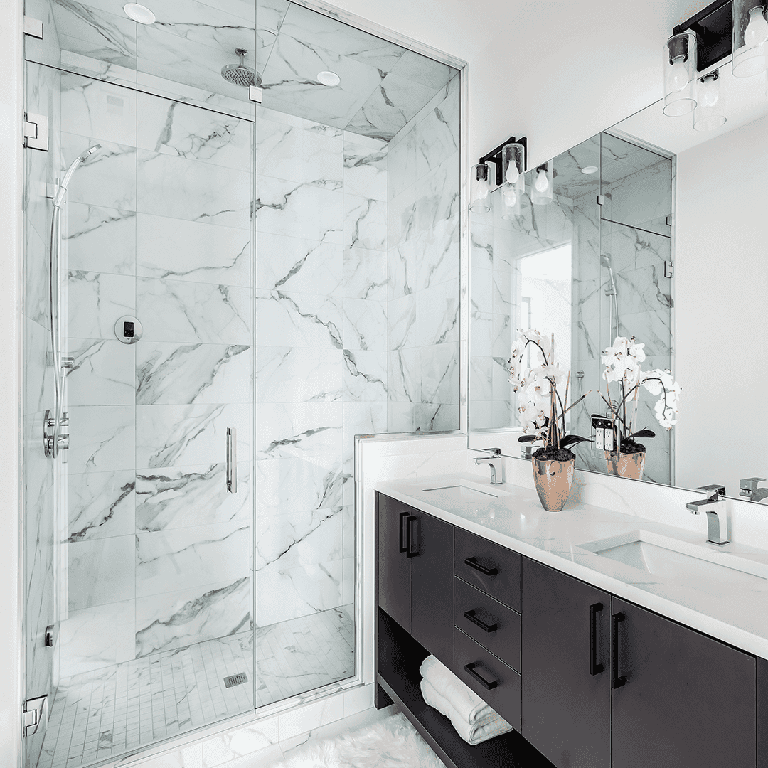 Modern bathroom featuring custom glass shower doors, a sleek vanity with tempered glass accents, and a beautifully beveled glass edge mirror, creating a stylish and functional space.