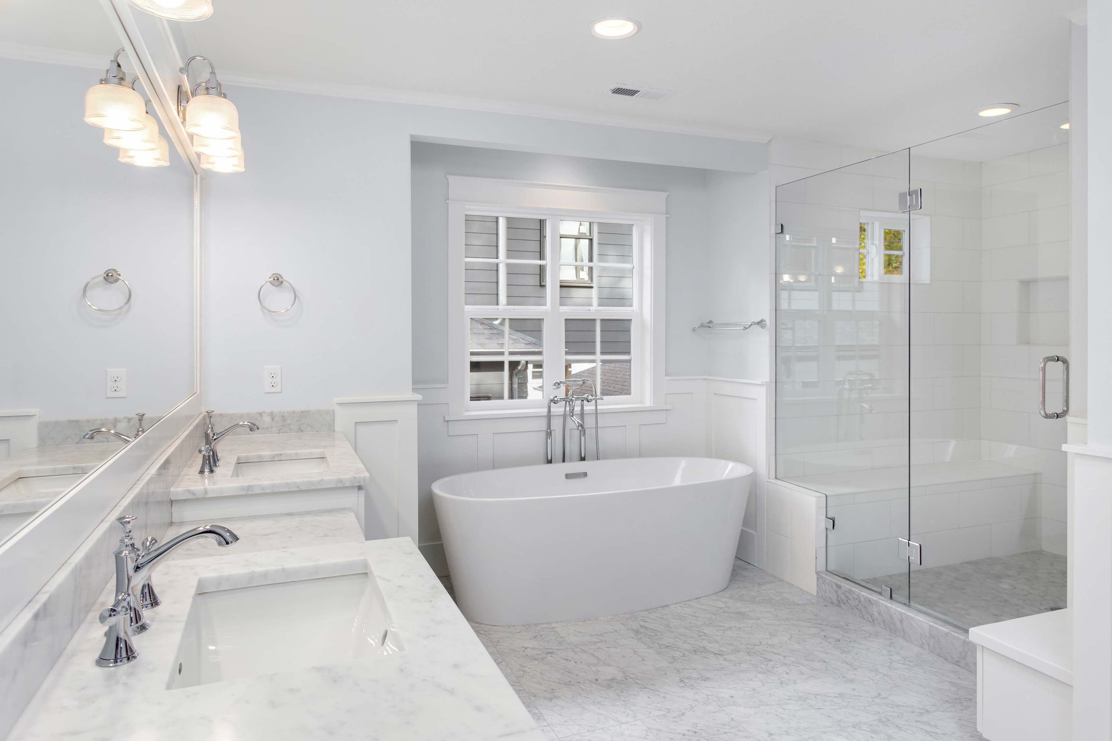 Stylish bathroom featuring custom shower doors, elegant mirrors with beveled glass edges, and a marble countertop, showcasing the versatility of tempered glass designs.