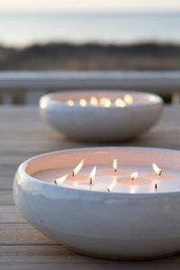 Two candles on a wooden table in a beach setting