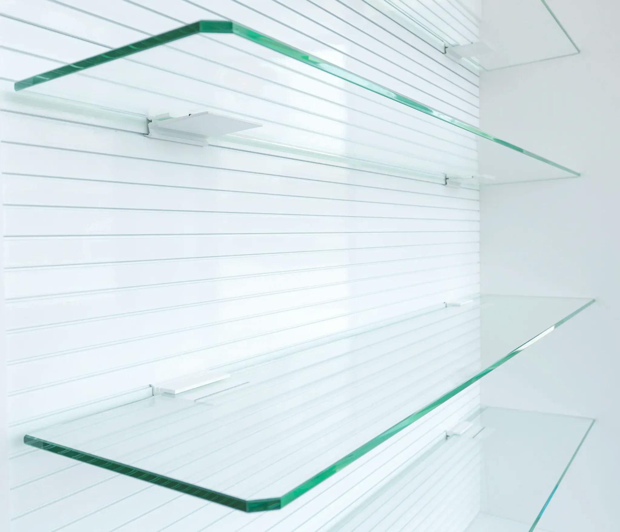 Two glass shelves with rounded corners, arranged for a business or pharmacy, mounted on a white wall