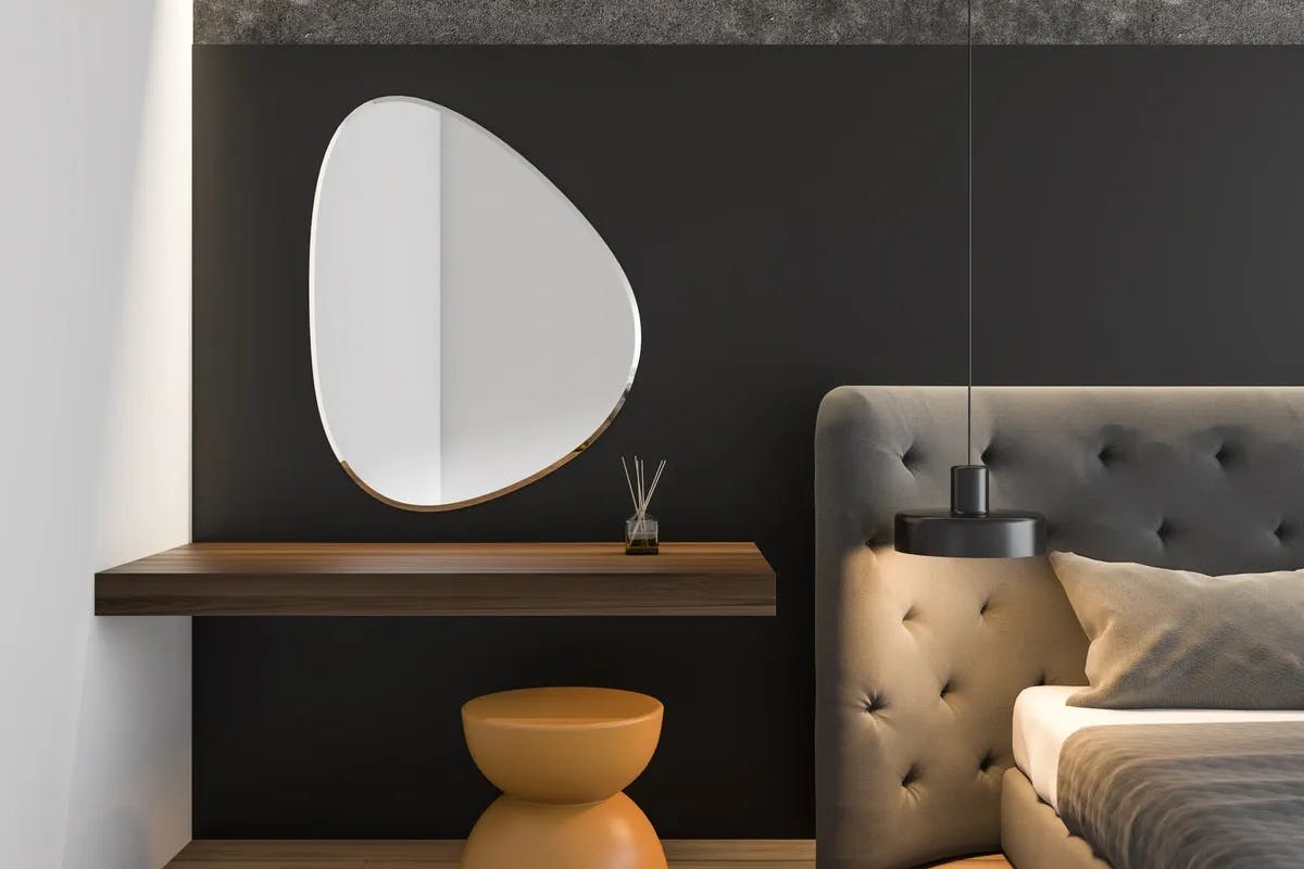 Custom egg shaped mirror hanging above side table in bedroom with dark gray color theme