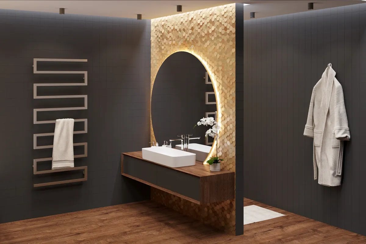 black painted walls around a vanity with gold accents. A round back lit mirror is on a gold accent wall on the vanity. 