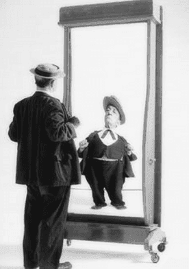 A person looking into a funhouse mirror that distorts their reflection