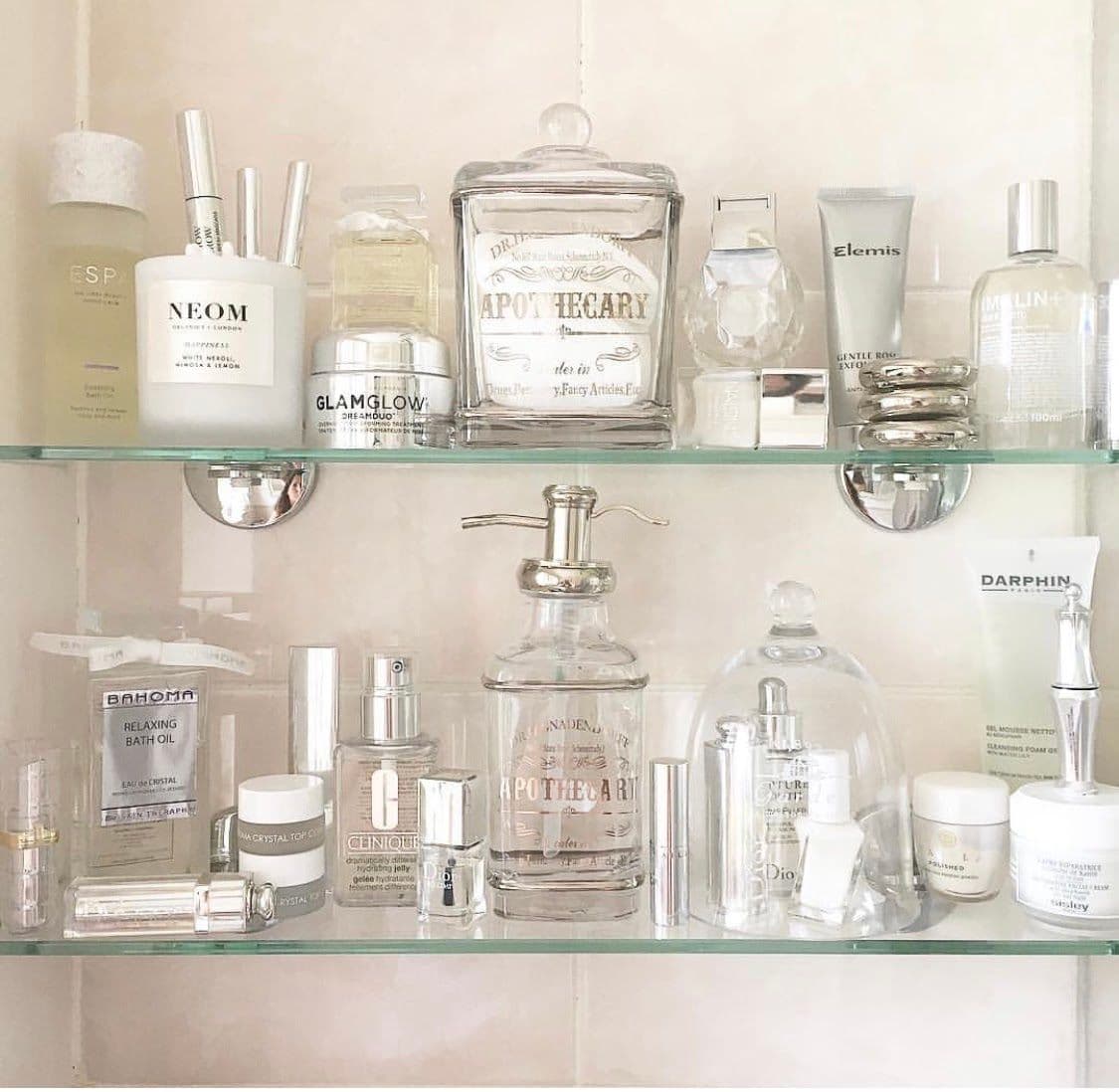 Glass shelving displaying various skincare and beauty products, highlighting custom glass solutions ideal for shower doors, table tops, and mirrors with a stylish, organized aesthetic featuring tempered and beveled glass edges.