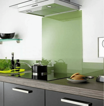 Kitchen setting with an electric stove and a green glass backsplash, featuring a glass shelf in the background.