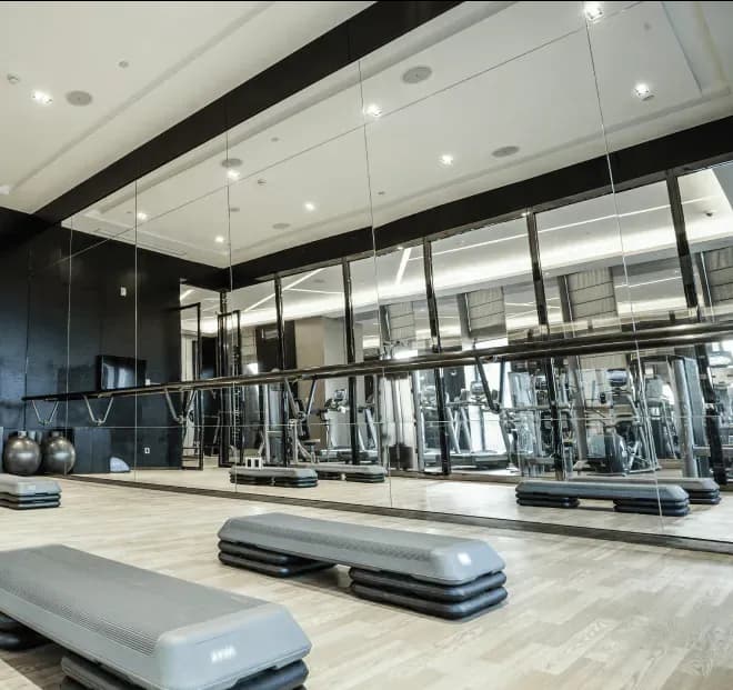 Mirrors on the wall of a modern gym, showcasing custom glass solutions for interior design, ideal for fitness spaces, emphasizing tempered glass durability and sleek aesthetics.