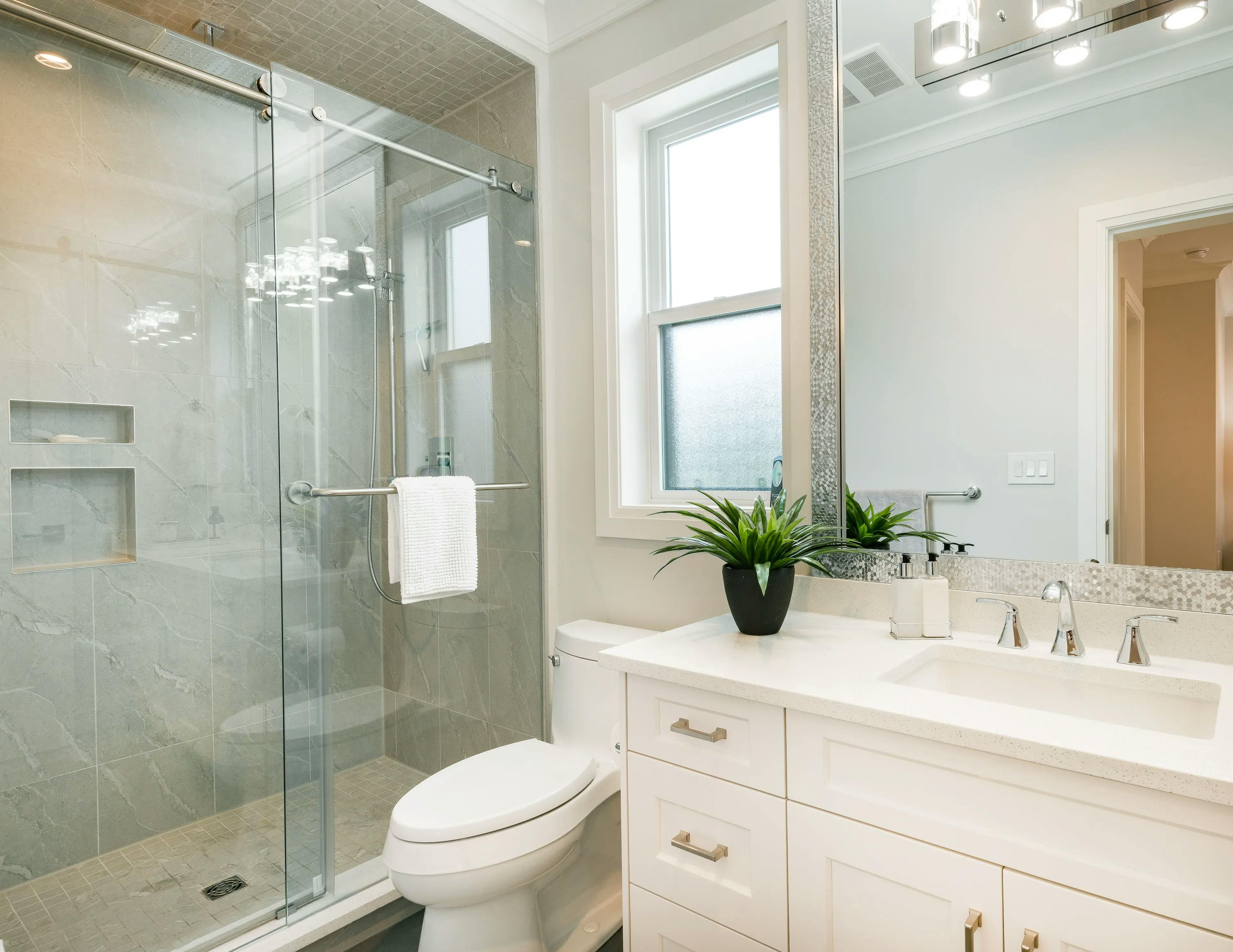 Bathroom setting featuring a vanity with a mirror, a toilet seat, and sliding glass doors