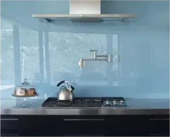 Kitchen setting featuring a stove and a light blue glass backsplash