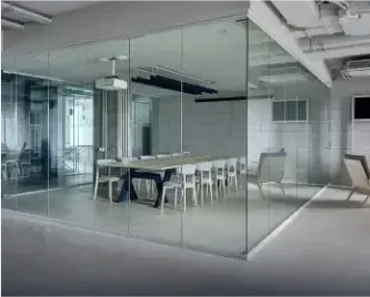 Office setting with a meeting room featuring clear glass walls