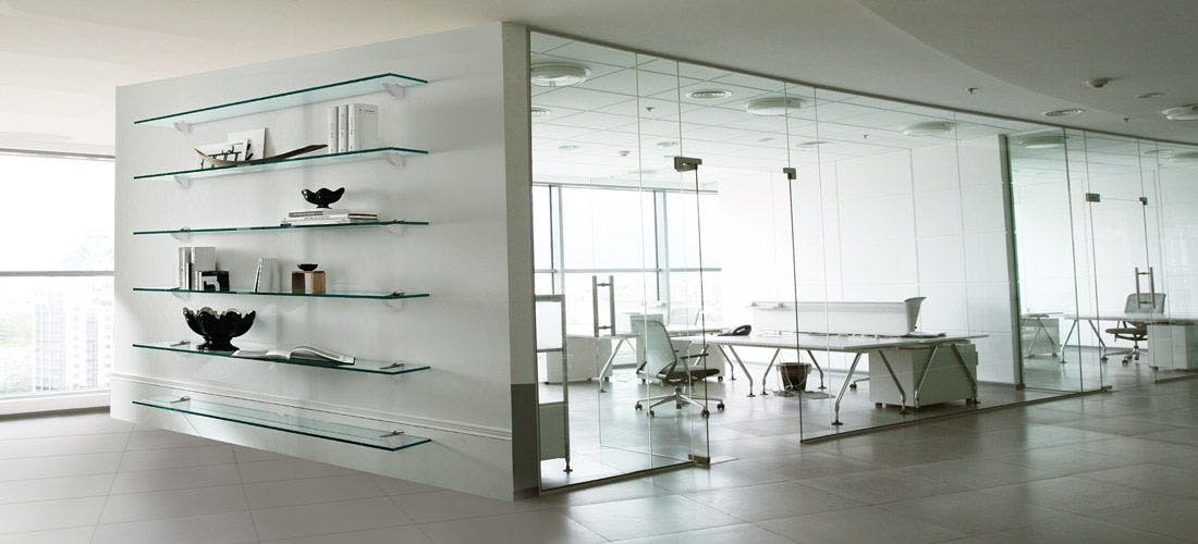 Glass walled office with desk and shelves, featuring custom glass shelves for a sleek and modern look.