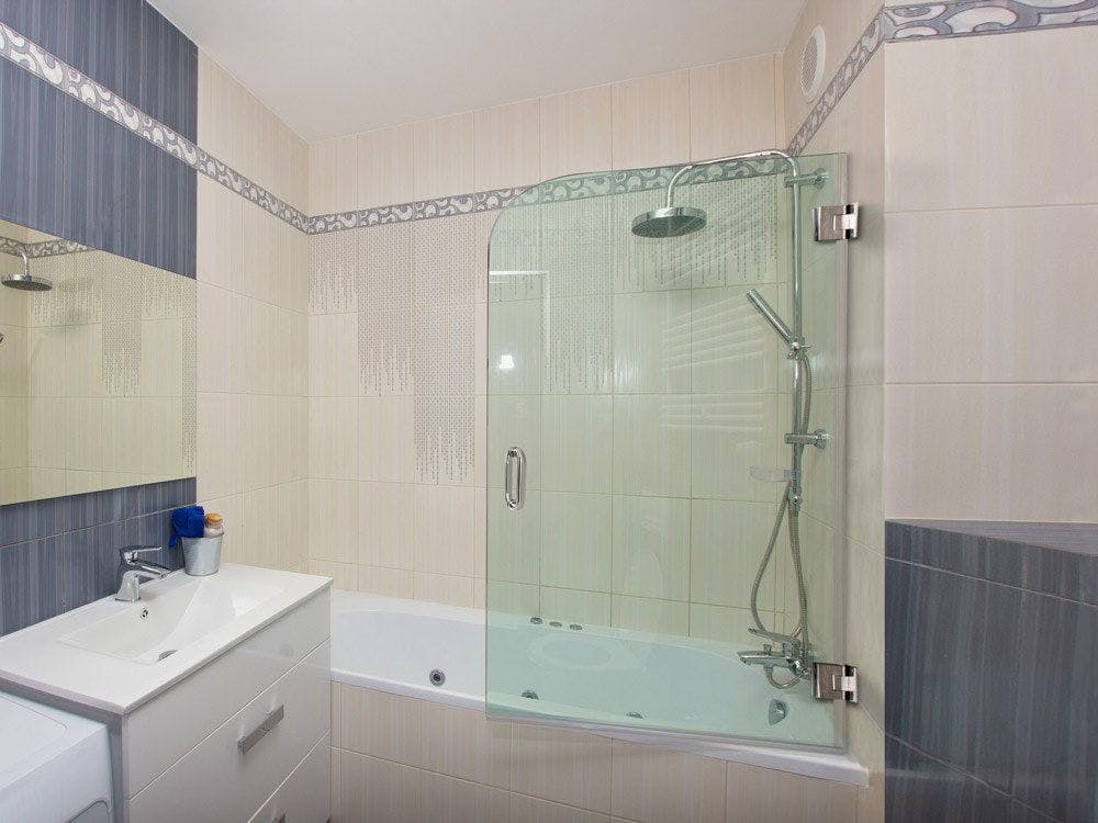 White bathtub with beige tiled walls