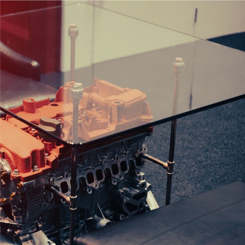 Custom glass tabletop resting on an engine block, showcasing tempered glass with a clear finish and sleek design, suitable for modern interiors.