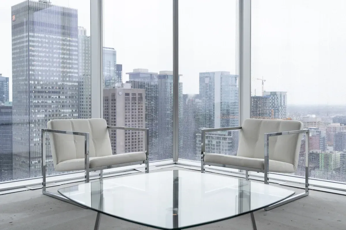 Modern lounge area featuring a sleek glass table, perfect for showcasing custom glass designs like tempered and beveled glass edges, with a stunning city view in the background.