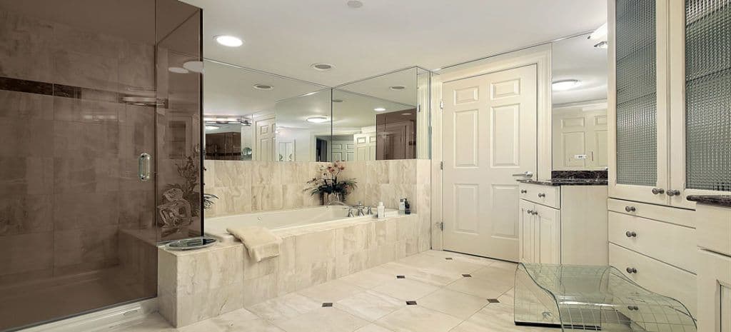Luxurious bathroom featuring custom glass shower doors, elegant beveled glass mirrors, and a stylish countertop, showcasing premium tempered glass and contemporary design elements.