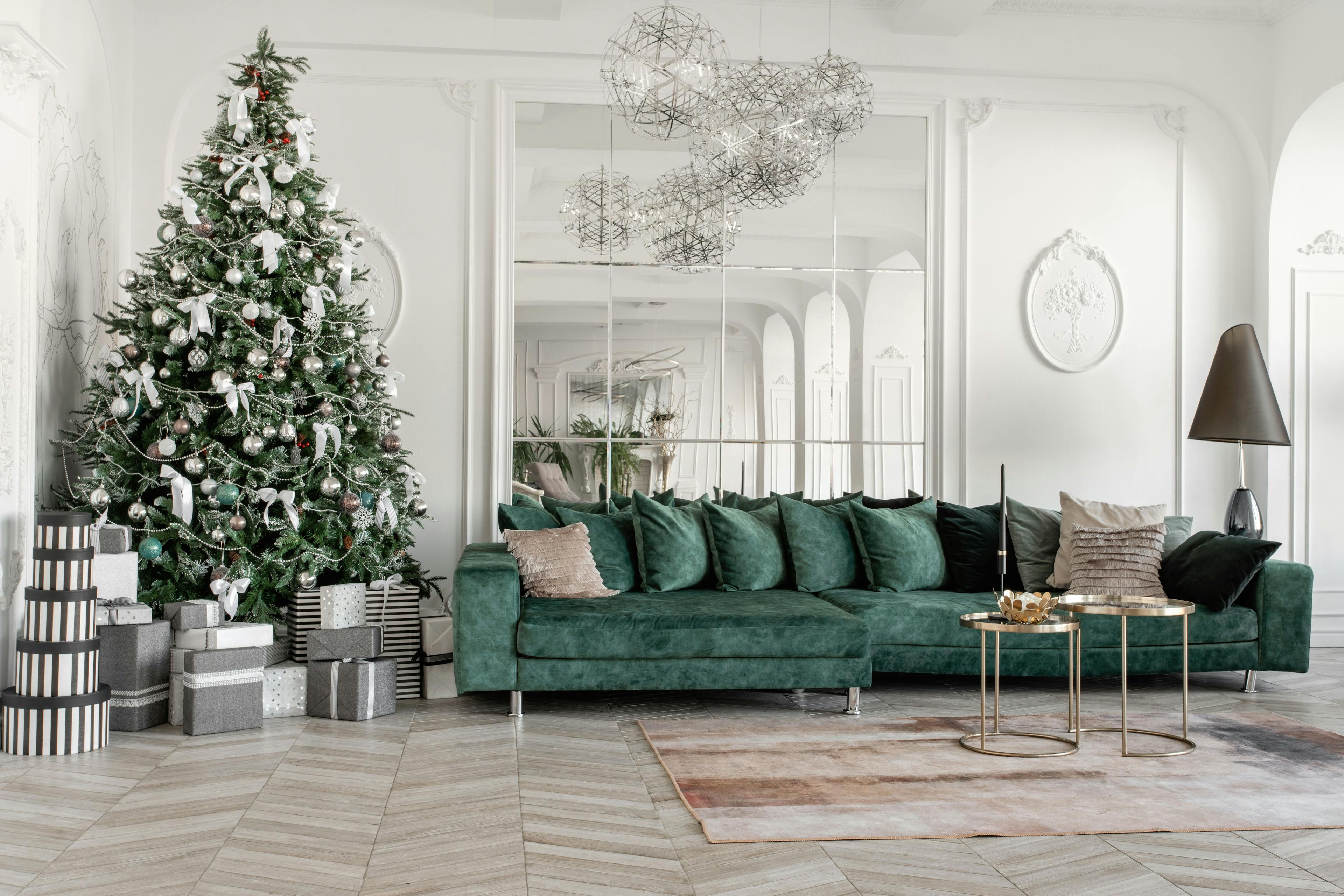living room with green velvet couch and christmas tree surrounded by presents in front of mirror tiles 