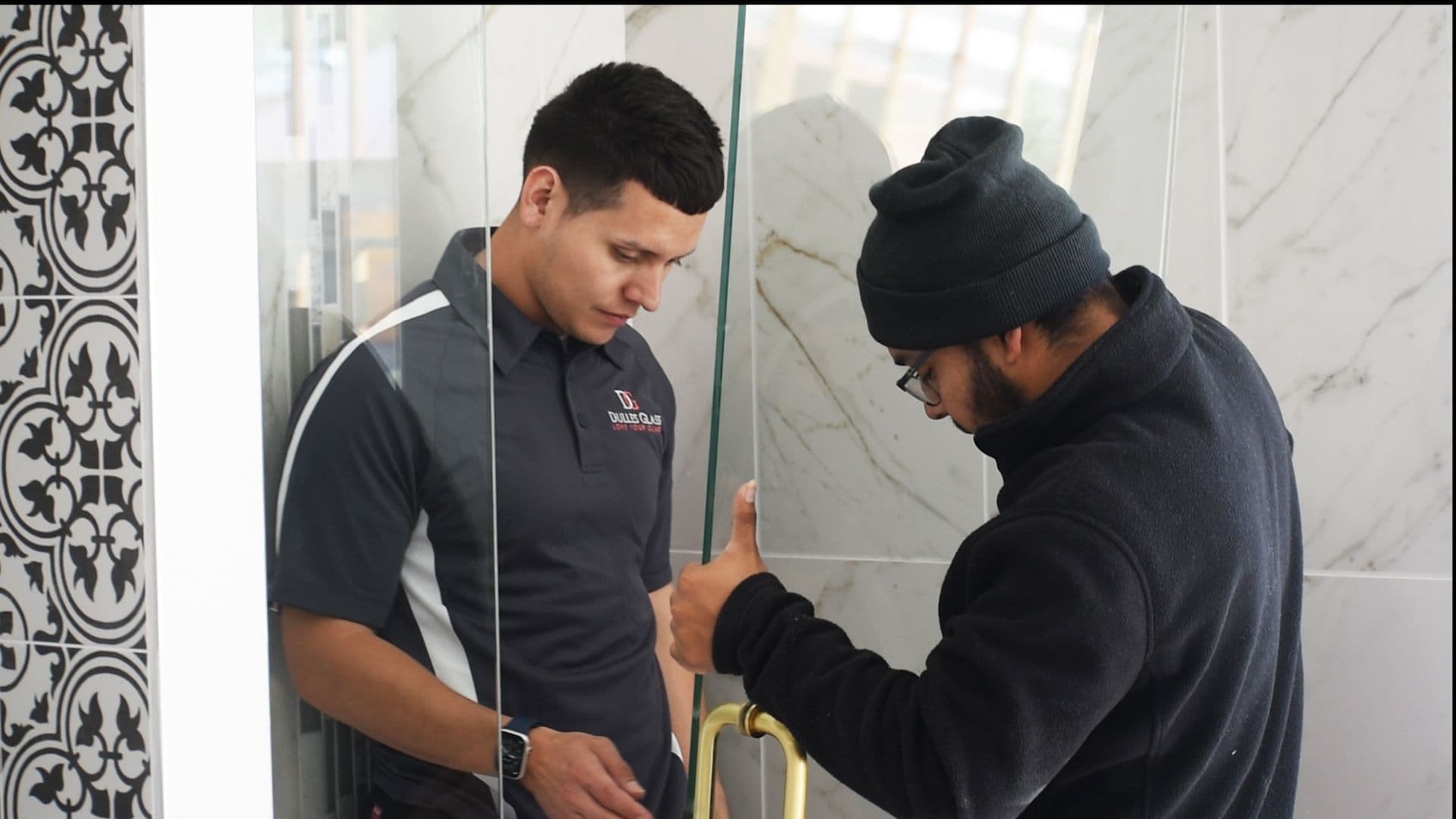 Two workers examine a custom glass shower door installation, showcasing tempered glass and innovative design elements.