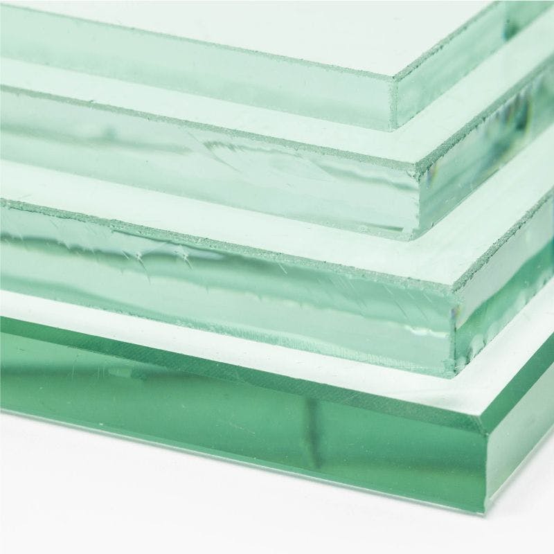 A pile of clear glass sheets neatly arranged on a white surface