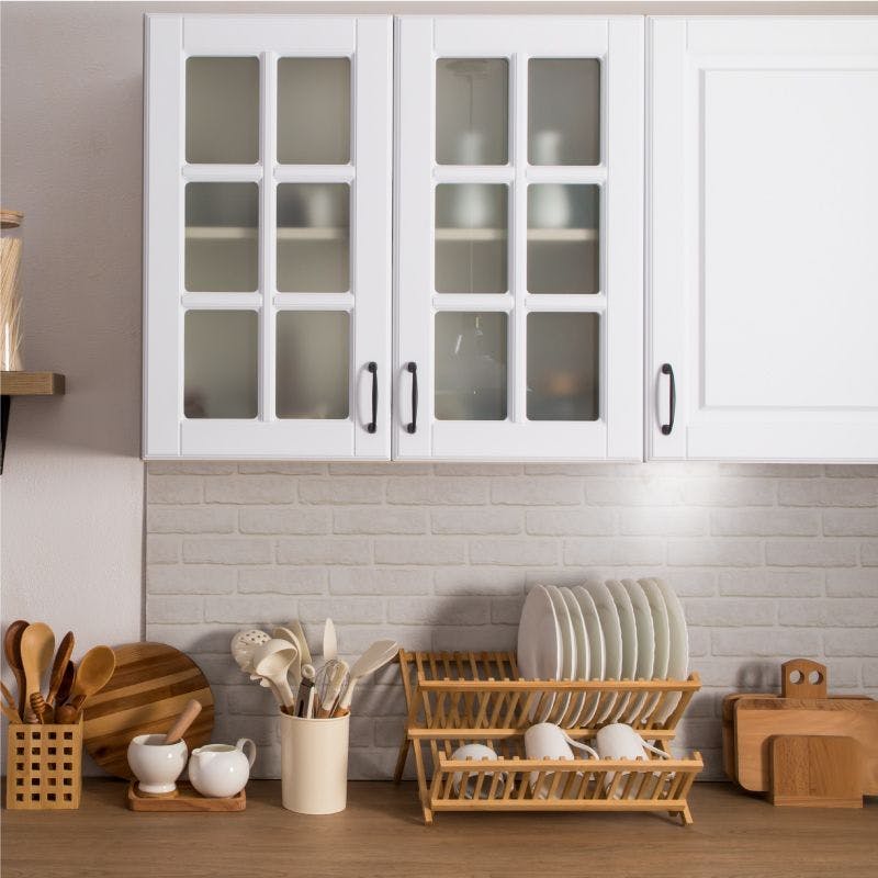 Kitchen cabinets with opaque glass, white doors and wooden shelves, providing a clean and natural storage solution