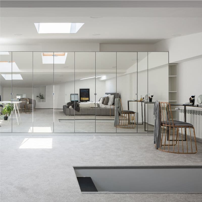 Modern interior featuring floor-to-ceiling custom mirrored sliding shower doors, reflecting stylish decor, with a focus on custom glass solutions for shower doors and mirrors.