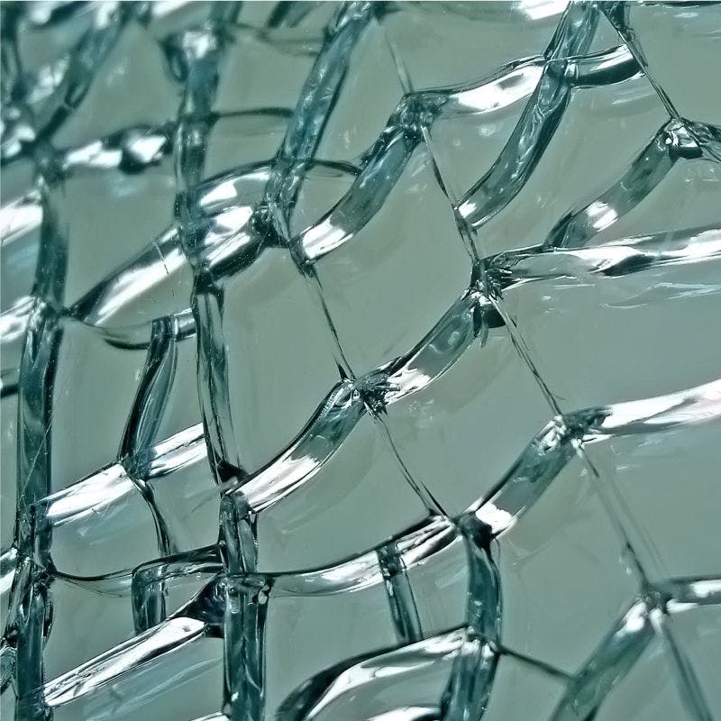 A close-up of a shattered glass window, revealing jagged edges and fragmented pieces.