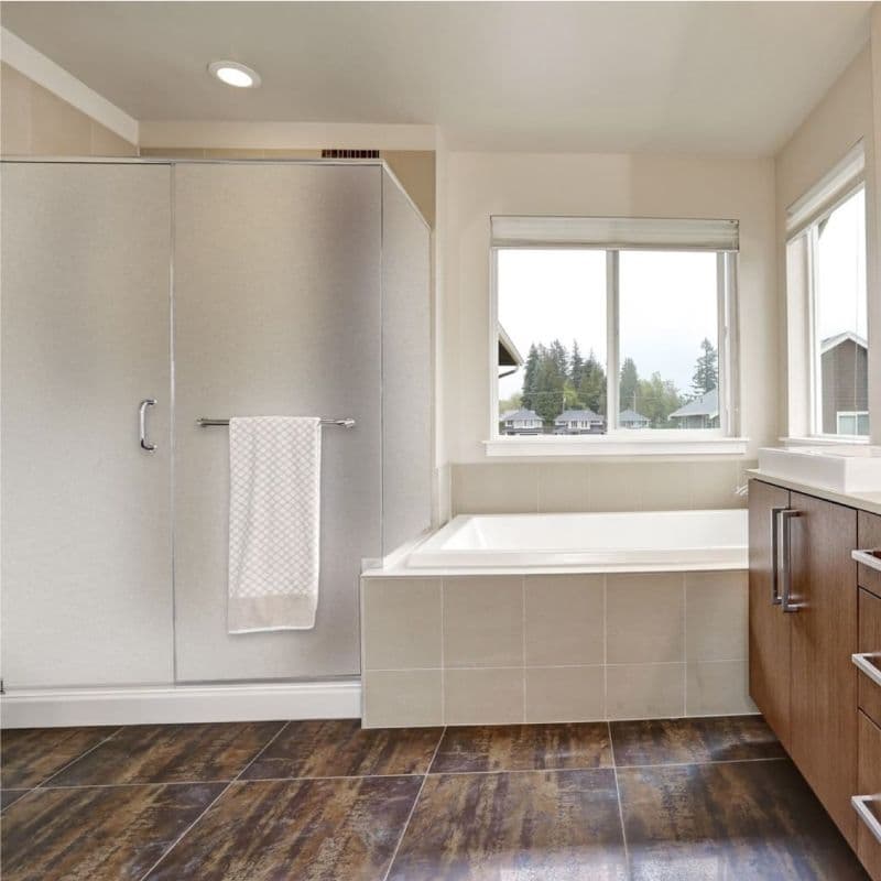 Modern bathroom featuring tempered glass shower doors, elegant bathtub, and sleek cabinetry, showcasing custom glass solutions and a stylish design aesthetic.