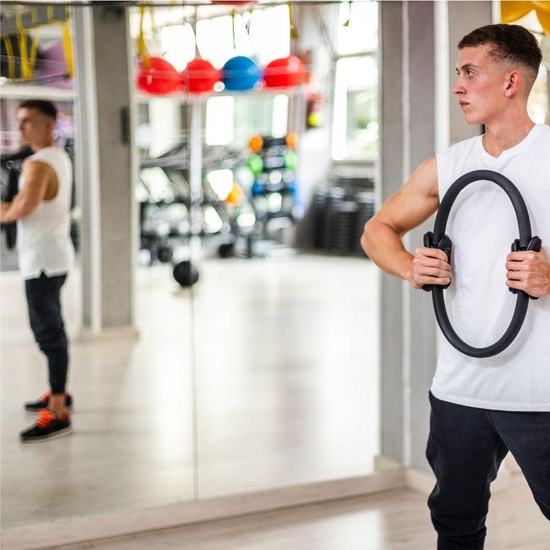 Man holding ring in gym in front of large gym mirror
