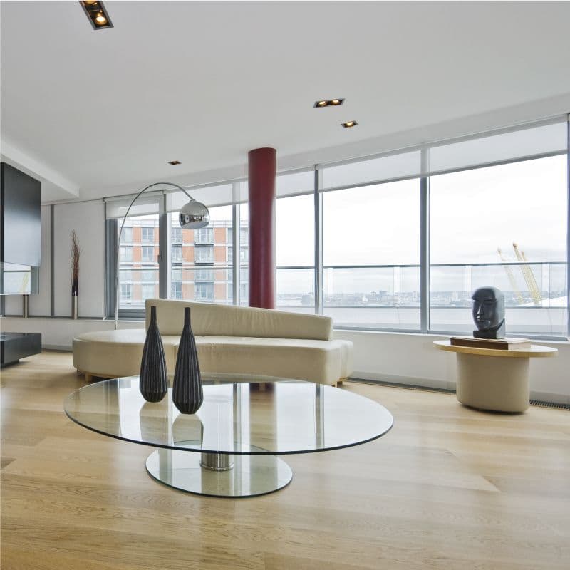 Modern living room featuring a glass coffee table, floor-to-ceiling windows, and elegant decor, showcasing custom glass and tempered glass elements.