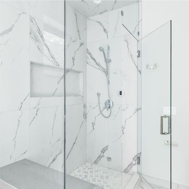 Custom glass shower doors featuring tempered glass in a modern marble shower design, highlighting sleek lines and a spacious feel.