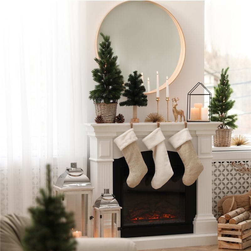 A cozy fireplace adorned with stockings and festive Christmas decorations, round mirror on top of fireplace, creating a warm and inviting holiday ambiance