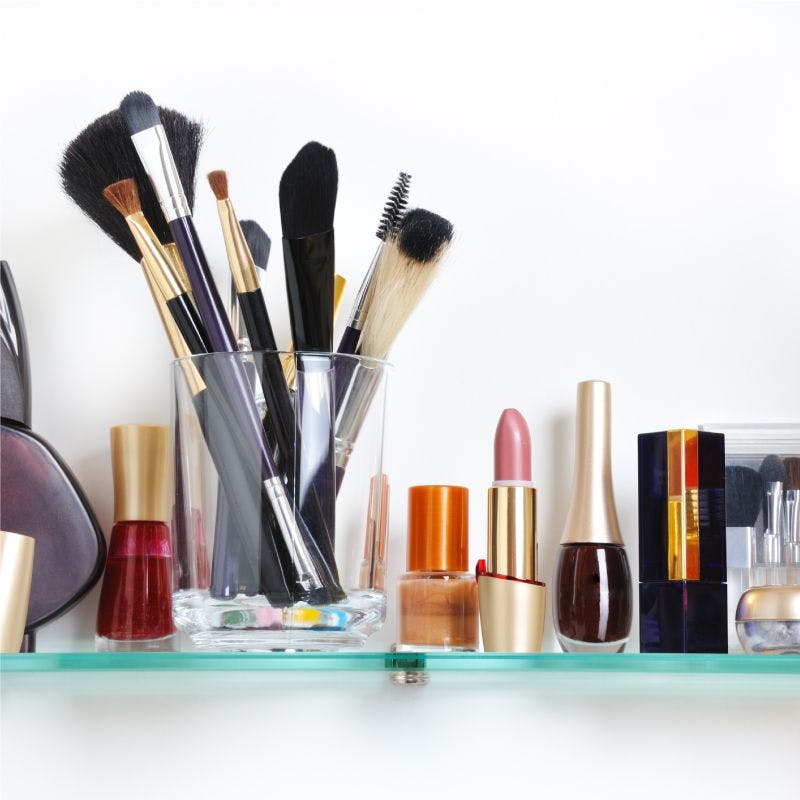 Makeup brushes and cosmetics on glass shelf
