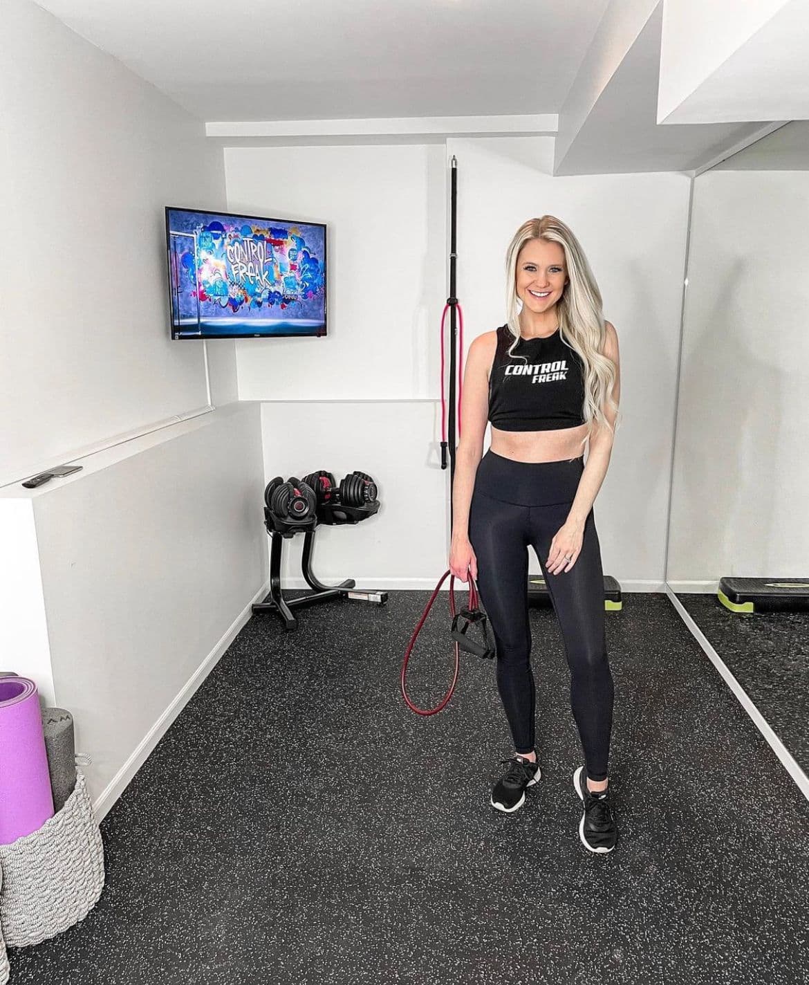 Fitness studio with custom mirrors, showcasing tempered glass elements, featuring a woman in activewear, exercise equipment, and a display screen.